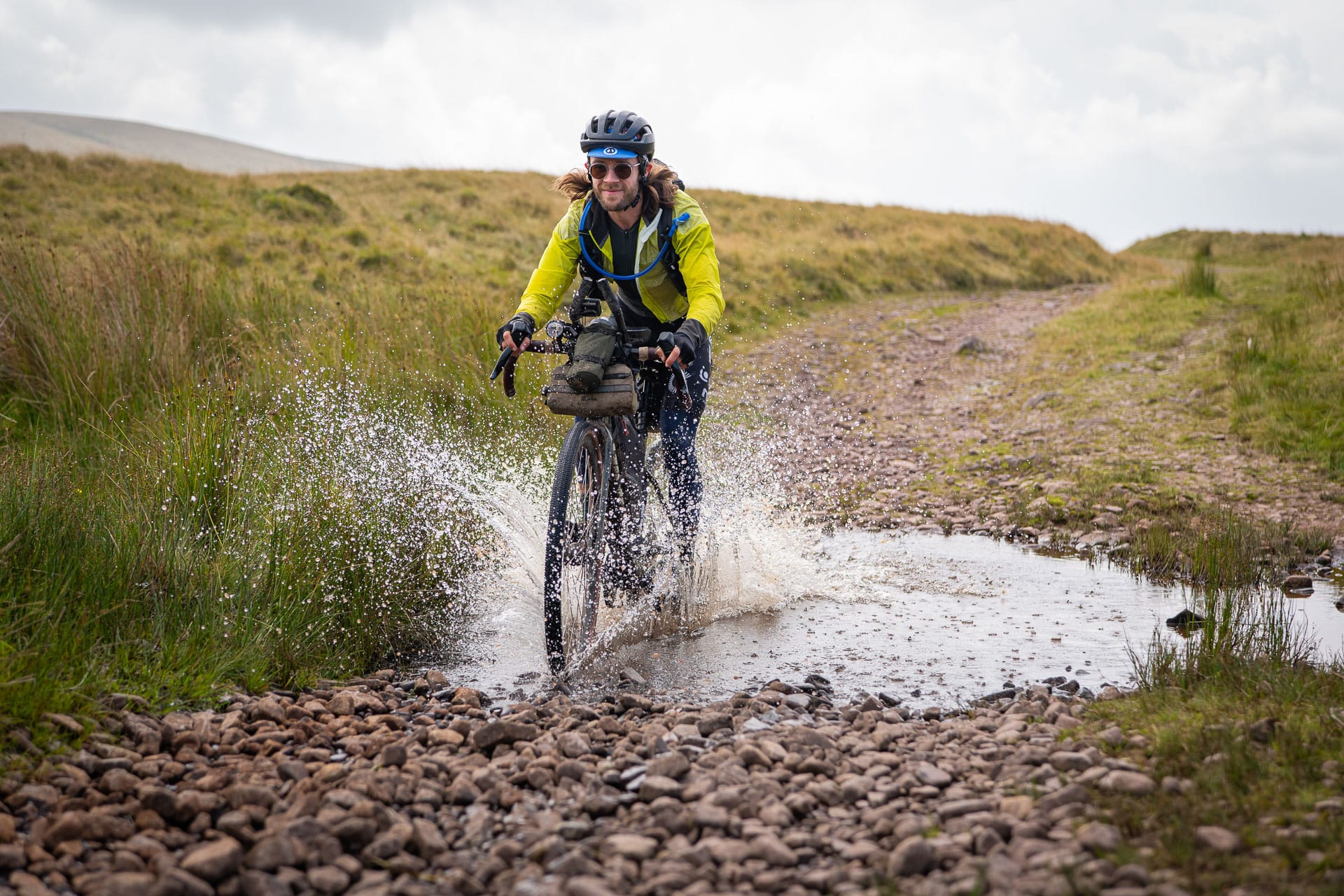 A rider splashing through a puddle on a gravel track near the Devil’s Elbow