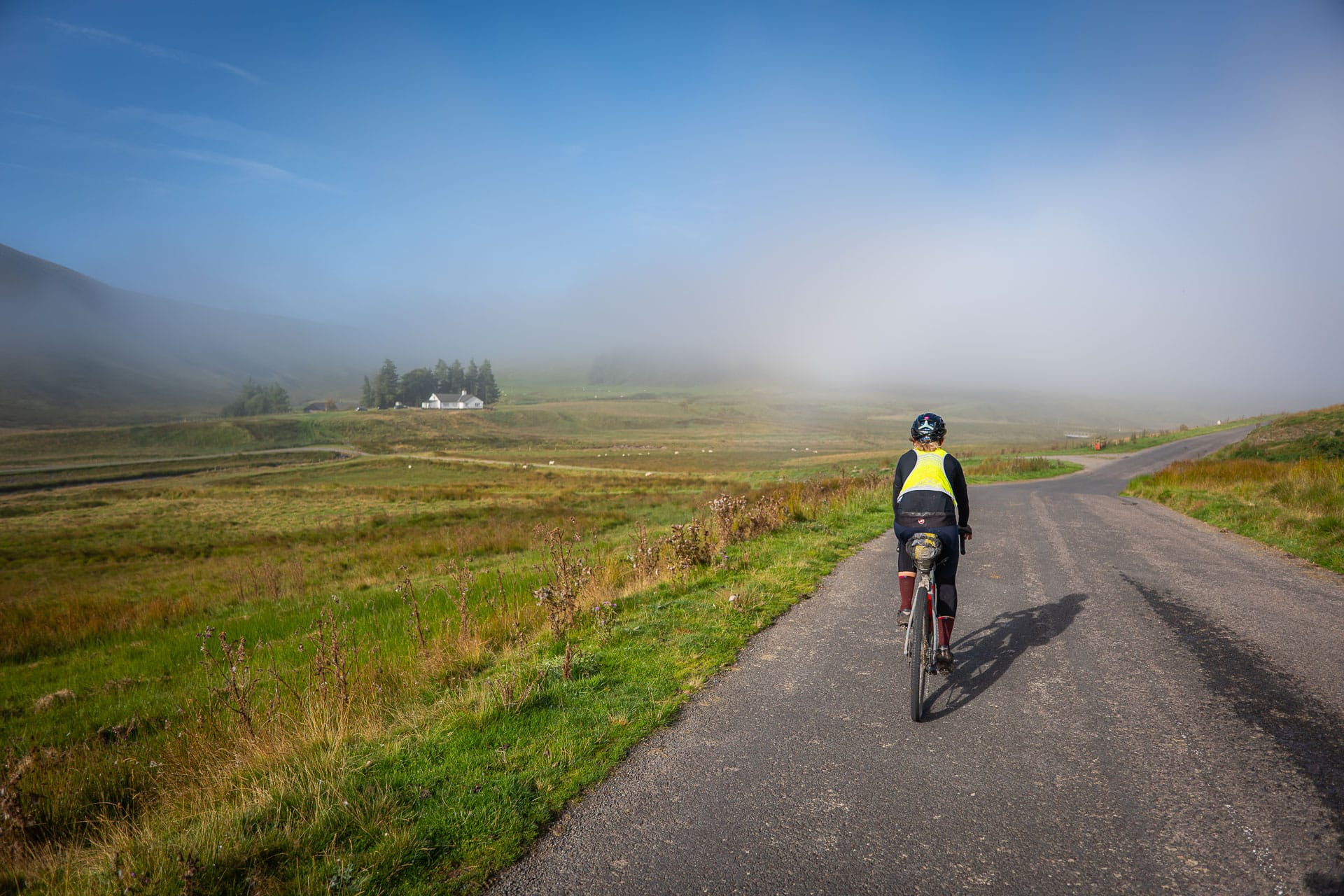 A rider on a road through the Elan Valley as mist lifts off the hills
