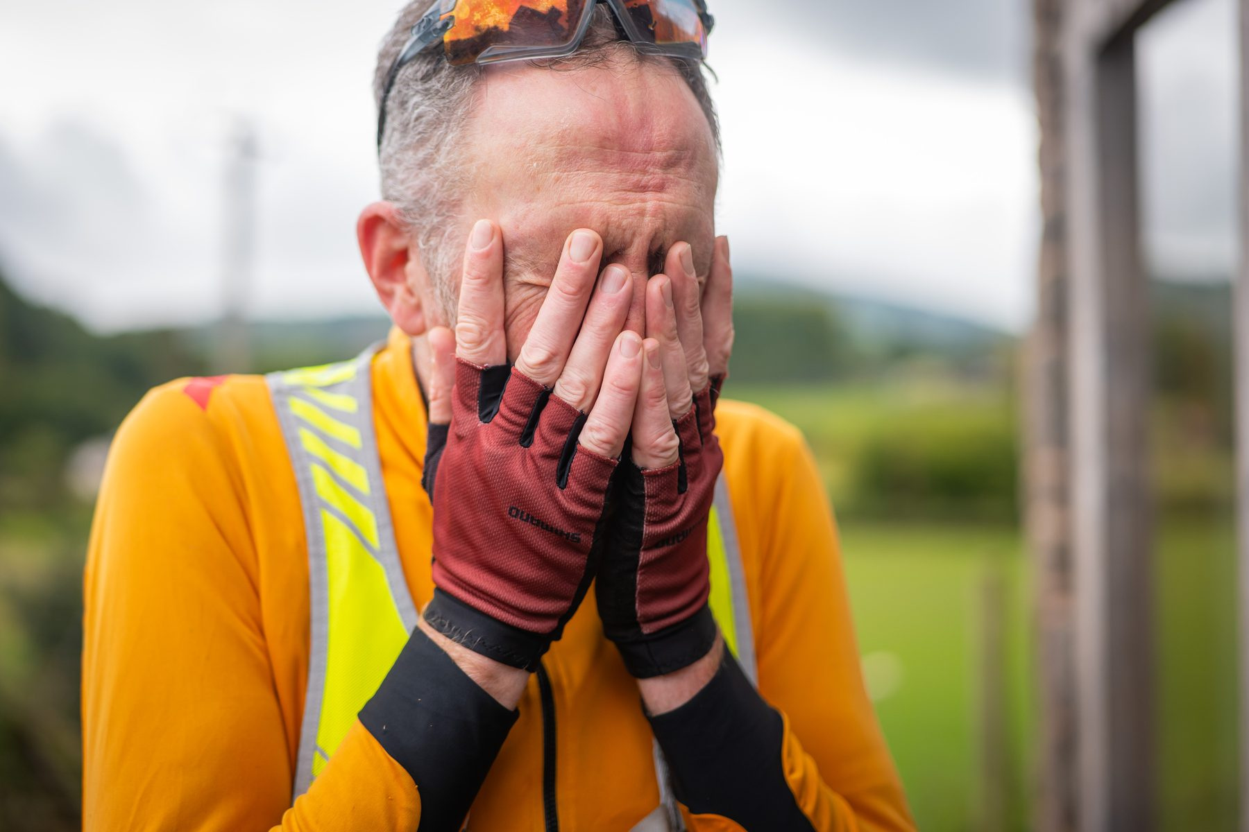 A rider with his face in his hands at the finish