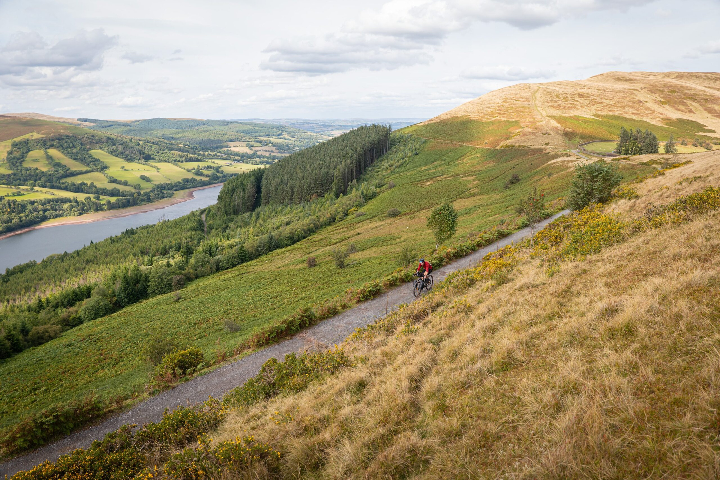 A rider on a gravel track high above a reservoir in the Bannau Brycheiniog