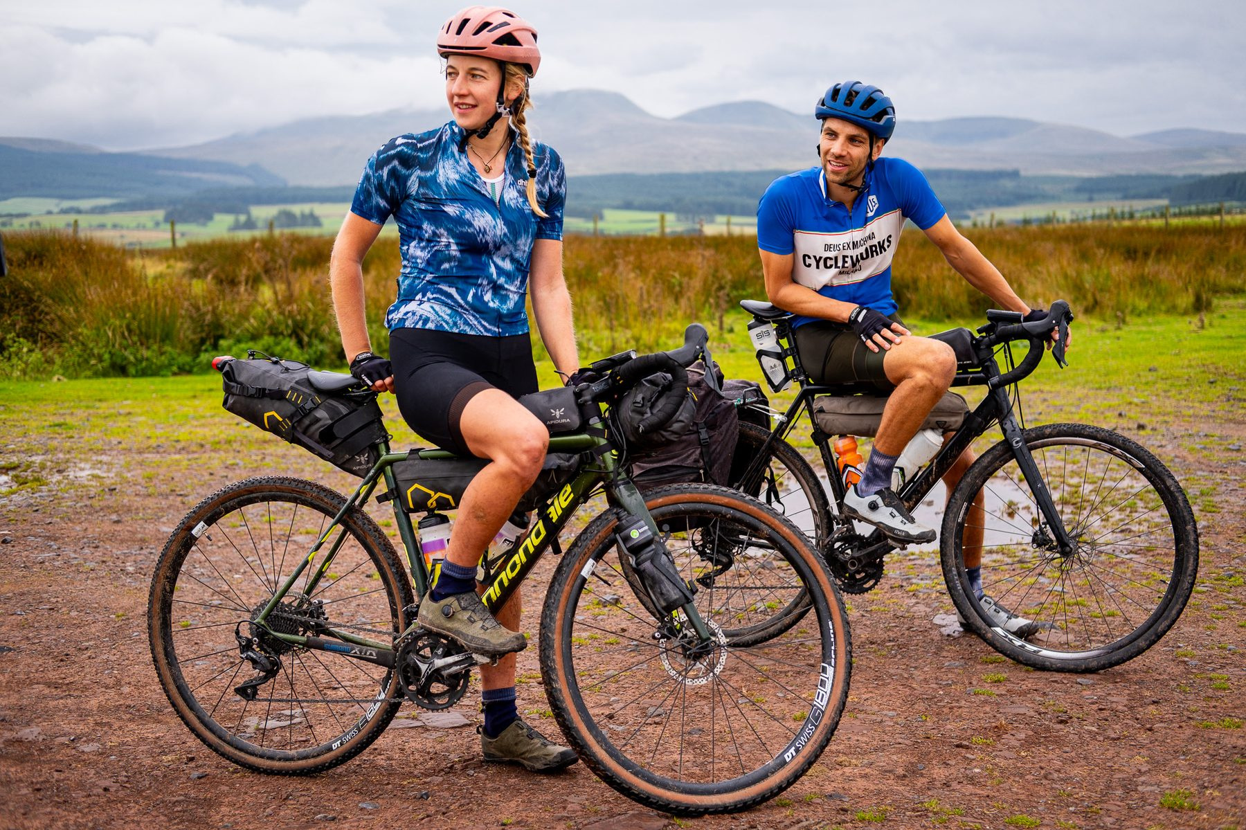 Two riders standing with their loaded bikes on open moorland