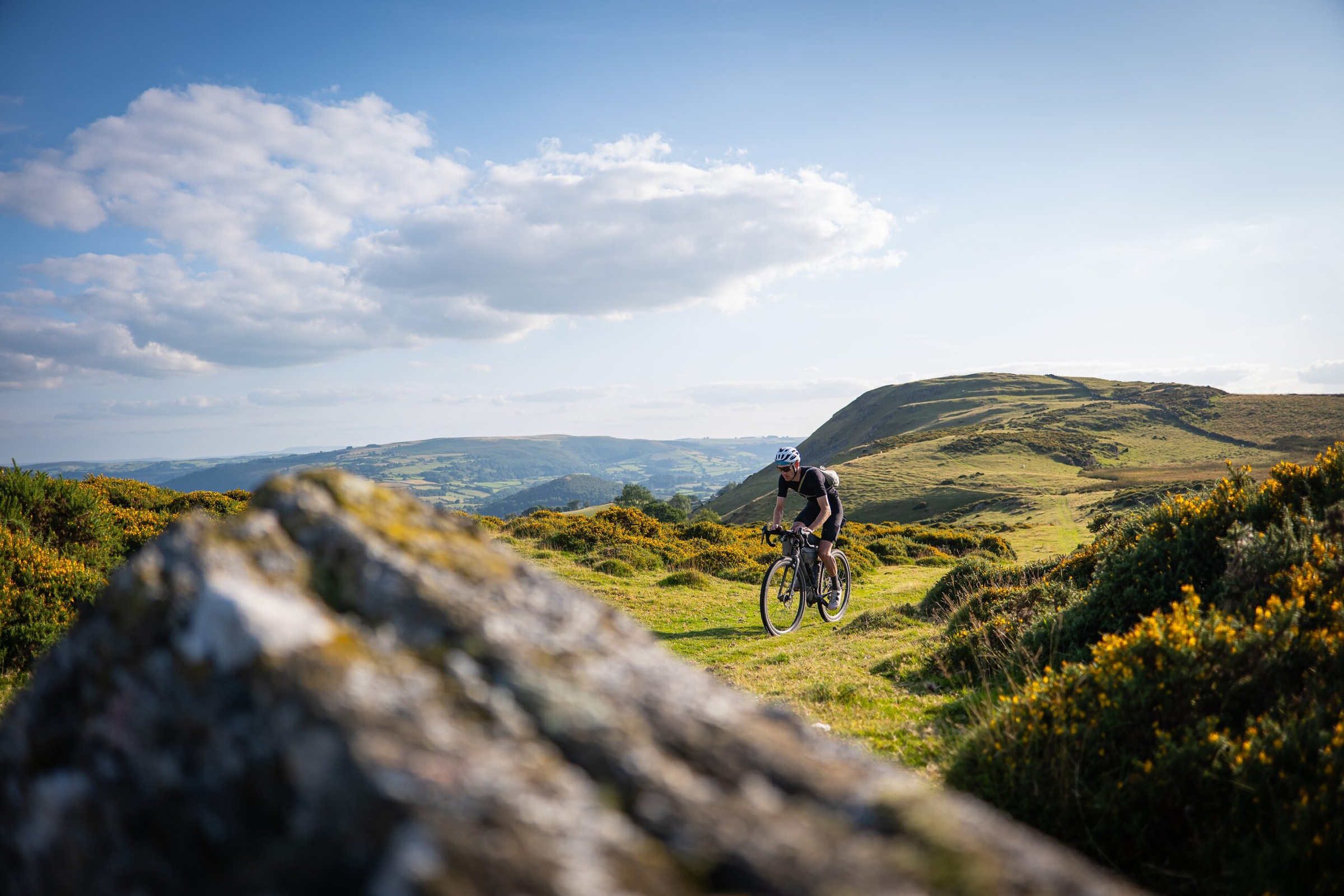 A rider on a grassy track between gorse and rocks above the hills near Builth Wells