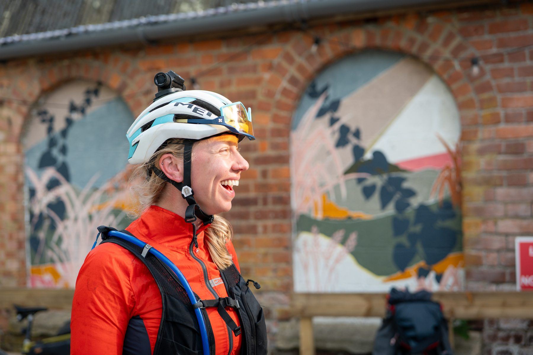 A rider in a red jacket laughing in front of a painted mural